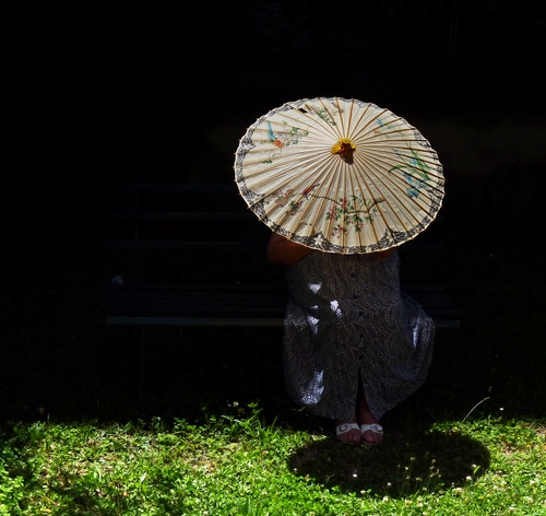 Immagine con ombrello, ombra, prato, erba, verde, panchina, piedi, donna, vestito, nero, cerchio, sole