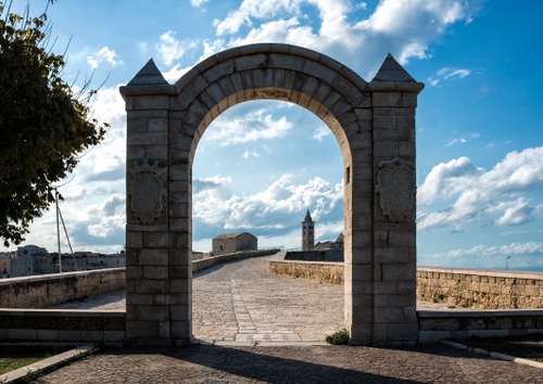 Immagine con arco, nuvole, campanile, strada, cielo, ombra, blu, albero