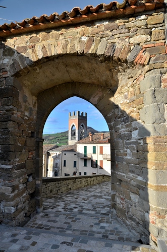 Immagine con arco, torre, pietre, strada, campanile, case, porta, merli, castello, scorcio, finestre, mattoni