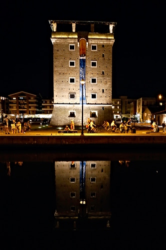 Immagine con torre, riflesso, luci, acqua, finestre, notturno, notte, persone, lampione, riflessi