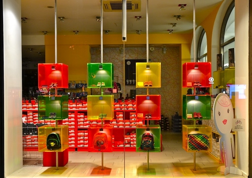Immagine con negozio, vetrina, scarpe, scatole, rosso, giallo, verde, zaini, faretti, colori, quadrati, vetrine, borse, cubi, vendita, esposizione