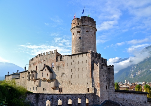 Immagine con castello, torre, nuvole, bandiere, merli, cielo, montagna, trento, mura