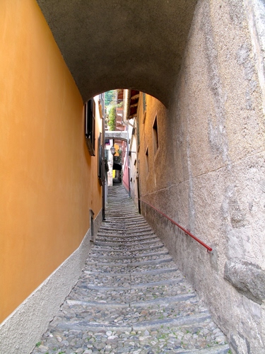 Immagine con vicolo, gradini, arco, finestre, archi, corrimano, borgo, salita, muro, scorcio, scale, scala, giallo, palazzi, sassi, paese, arancione, case