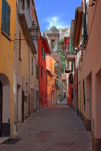 Immagine con vicolo, campanile, case, porte, finestre, cielo, balconi, rosso, strada, lampione, azzurro, lampioni, rudere, giallo, tombini