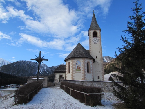 Immagine con campanile, croce, chiesa, nuvole, neve, montagna, siepe, cielo, orologio