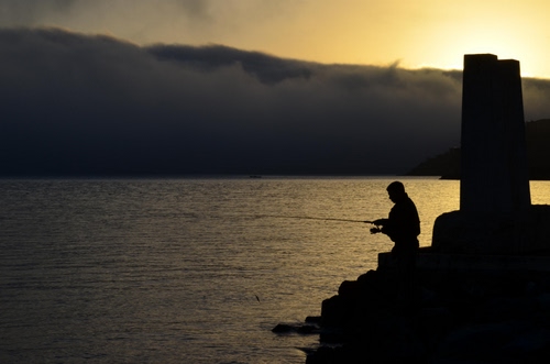 Immagine con pescatore, canna, acqua, controluce, nuvole, tramonto, mare, pesca, cielo, silhouette, nero, luce, alba, mulinello, sagoma, sole, pescare, nebbia