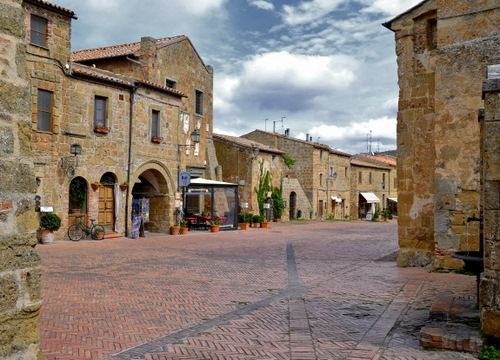 Immagine con piazza, nuvole, case, cielo, borgo, paese, finestre, arco