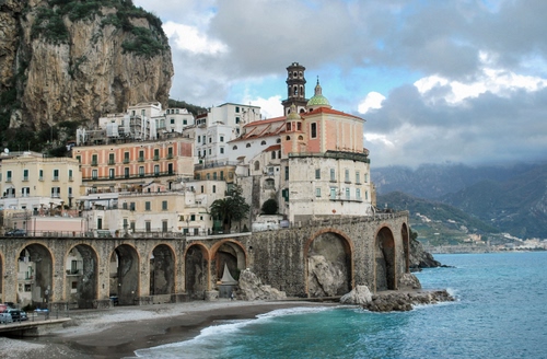 Immagine con mare, spiaggia, archi, nuvole, campanile, case, chiesa, acqua, cielo, finestre, costa, scogli, onde, strada, scorcio, paese, borgo