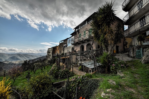 Immagine con nuvole, cielo, case, alberi, piante, borgo, montagne, balconi, paese, verde, panorama