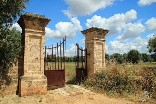 Immagine con cancello, nuvole, pilastri, cielo, alberi, campagna, colonne, aperto
