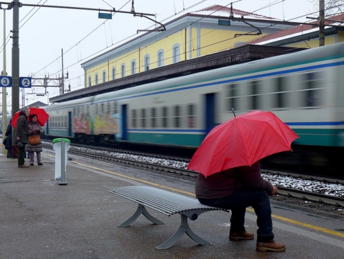 Immagine con stazione, treno, panchina, ombrelli, rosso, ombrello, binari, persone