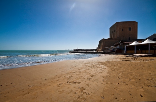 Immagine con mare, sabbia, spiaggia, cielo, torre, acqua, controluce, ombrelloni