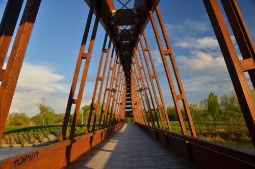 Immagine con ponte, nuvole, cielo, alberi, fiume, prospettiva, ferro, legno, strada, simmetria, verde, travi, acqua, ombra, ruggine