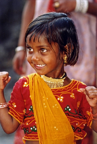 Immagine con rosso, bambina, sorriso, giallo, vestito, occhi, capelli, collana, pugni, orecchini, fascia, mani, indiana, india, sciarpa, denti, naso