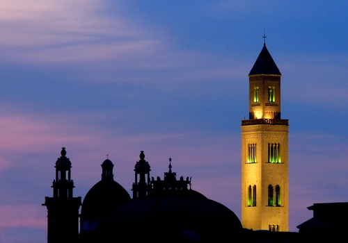 Immagine con cielo, campanile, luci, cupola, tramonto, croce, cupole, campanili, azzurro, blu, bifore, nero, quadrifore, tetto, chiesa, torri, nuvole, giallo, sera, silhouette, notturno