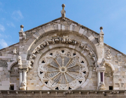 Immagine con rosone, chiesa, cielo, statue, colonne, archi, sculture, marmo, leoni, raggi, azzurro, pietra, facciata, arco, animali, cerchio, bianco, romanico, traforato