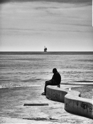 Immagine con mare, muretto, bianconero, uomo, orizzonte, persona, solitudine, onde, acqua, seduto, cielo, spiaggia, bicchiere, nero, nave, riva, controluce, nuvole, solo, graffiti