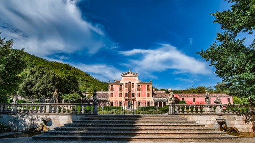 Immagine con alberi, nuvole, cielo, balaustra, villa, scalinata, verde, gradini, statue, scala, azzurro, cancello, palazzo, bianco, giardino, scalini, finestre, montagna