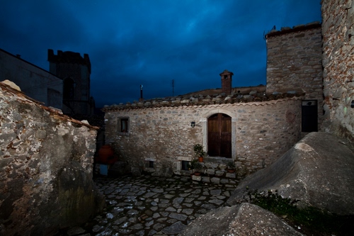 Immagine con torre, nuvole, porta, casa, pietre, muri, notturno, comignolo, case, cielo, pietra, scala, notte, portone, gradini, finestra, scalini, finestre, vicolo, borgo, vasi